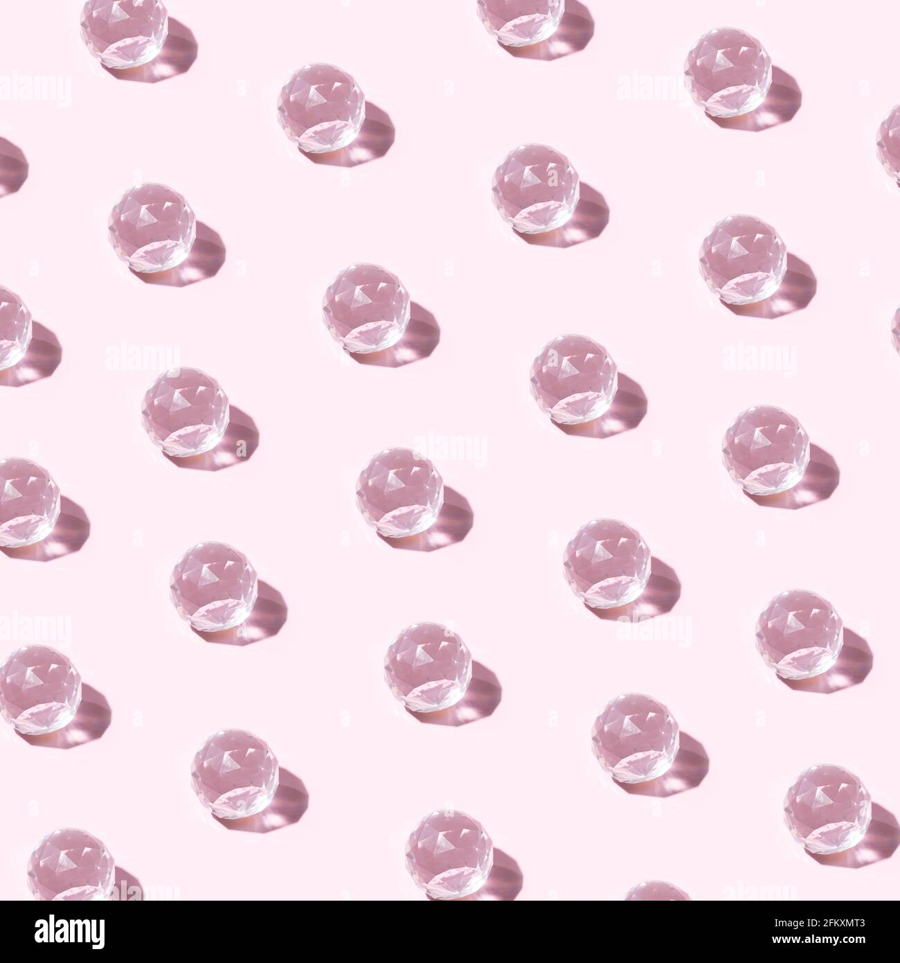 Motif en verre transparent brillant lumineux sur fond rose pastel. Concept créatif de rouleaux de baud minimum Banque D'Images