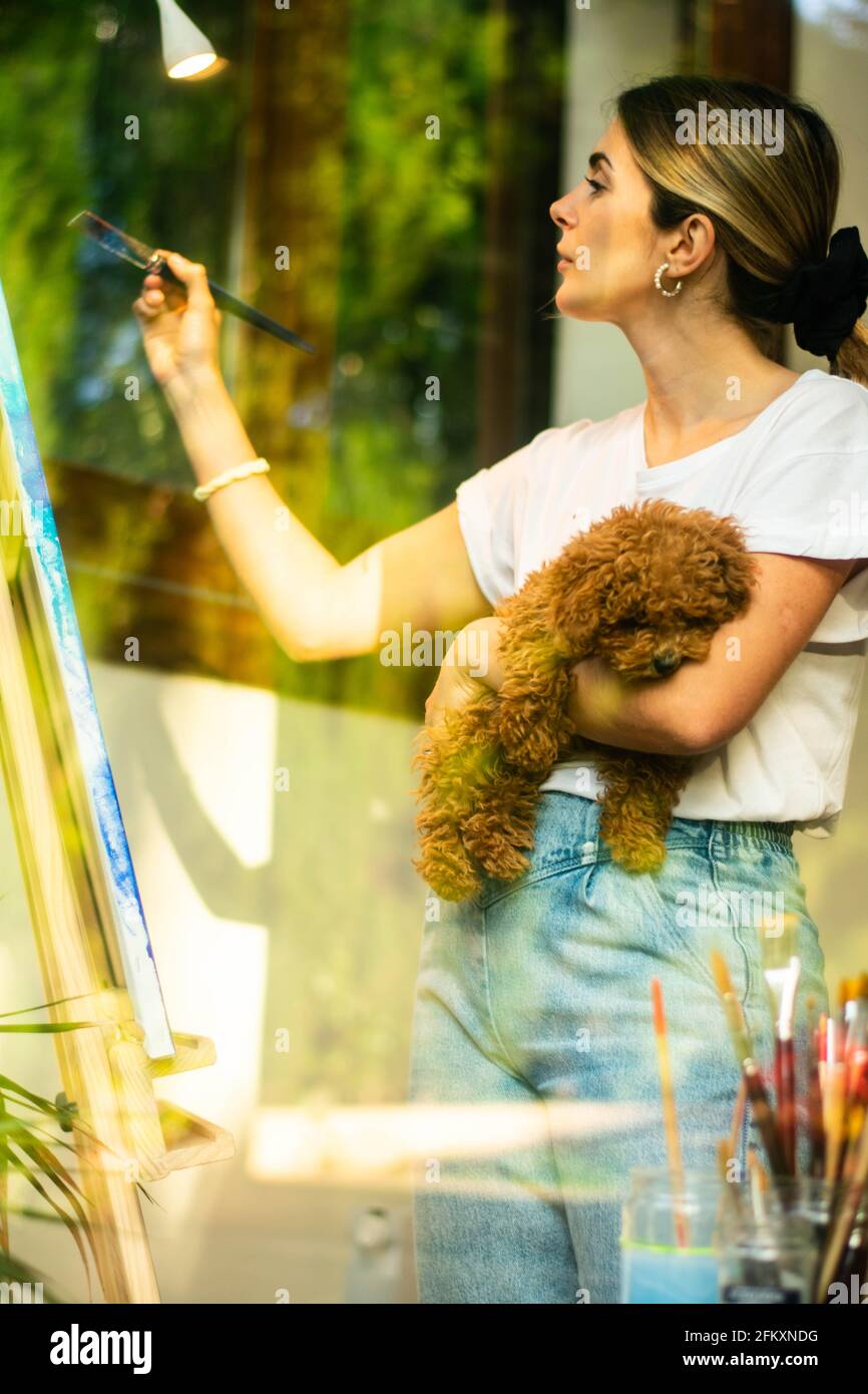 jeune fille blonde peint avec son animal de compagnie dans les classes virtuelles Banque D'Images