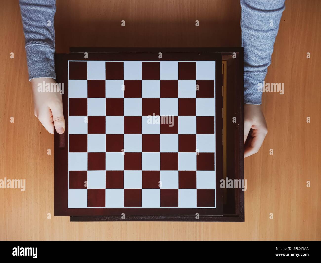 les mains des enfants et le plateau d'échecs sur fond de bois vue de dessus Banque D'Images