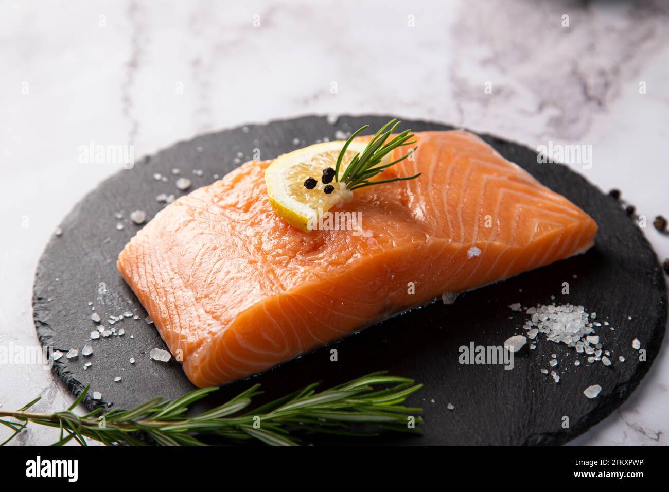 saumon cru servi sur une assiette d'ardoise avec citron et romarin sur la table Banque D'Images