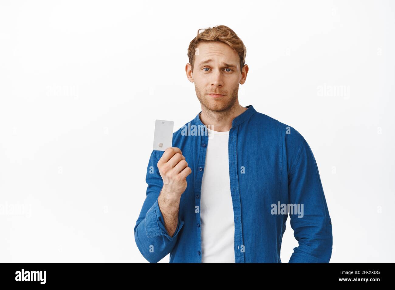 Un homme à tête rouge riche et sassy se vantant avec sa carte de crédit platine, en ayant l'air confiant et sans tracas, payant sans contact, avoir de l'argent sur le compte Banque D'Images