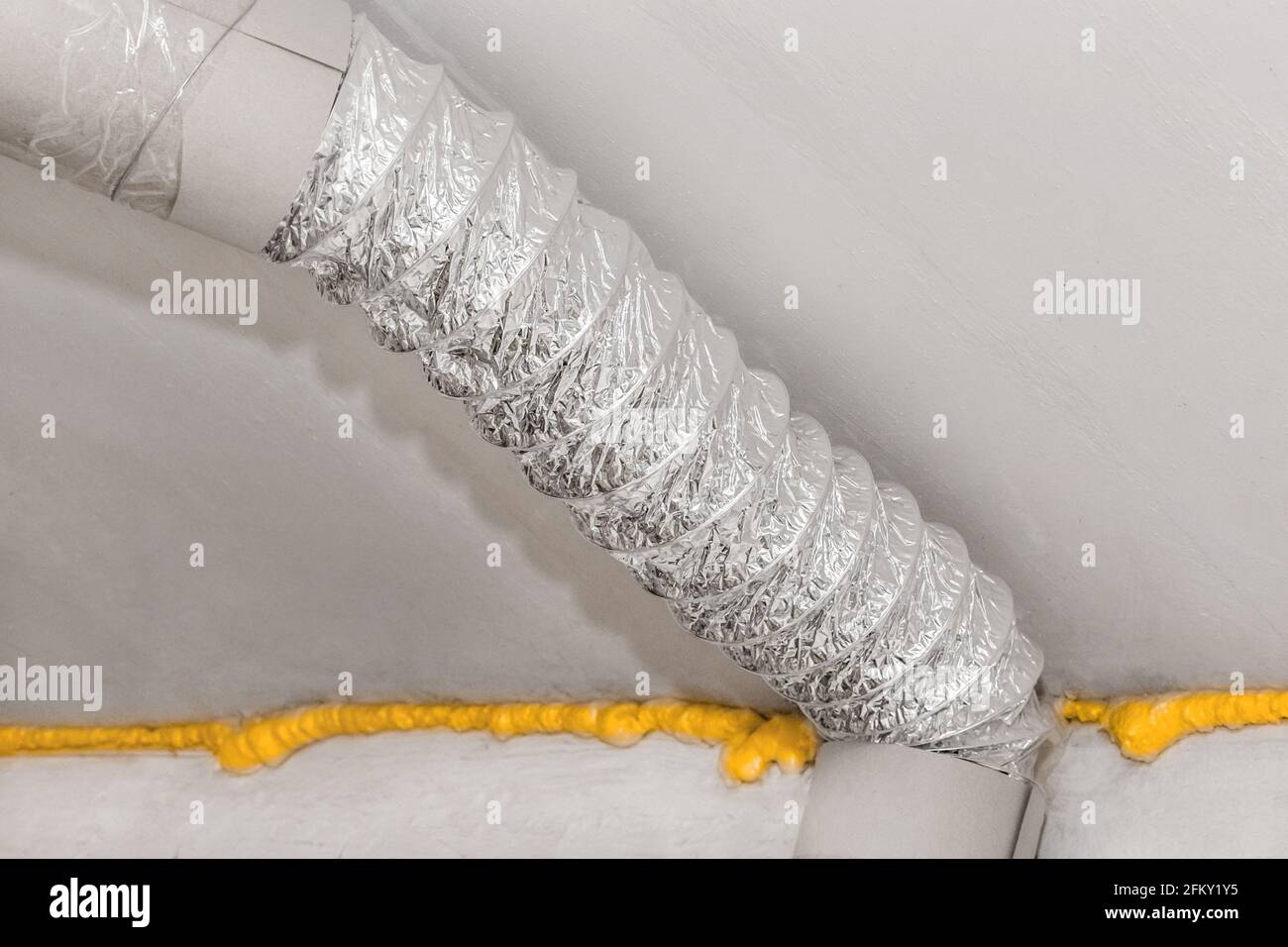 Ventilation tuyau métallique d'air sous plafond avec isolation en mousse de polyuréthane de construction dans une usine ou une usine industrielle. Banque D'Images