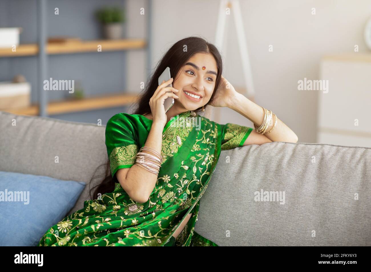 Belle femme indienne souriante dans la robe sari faire un appel téléphonique intérieur Banque D'Images
