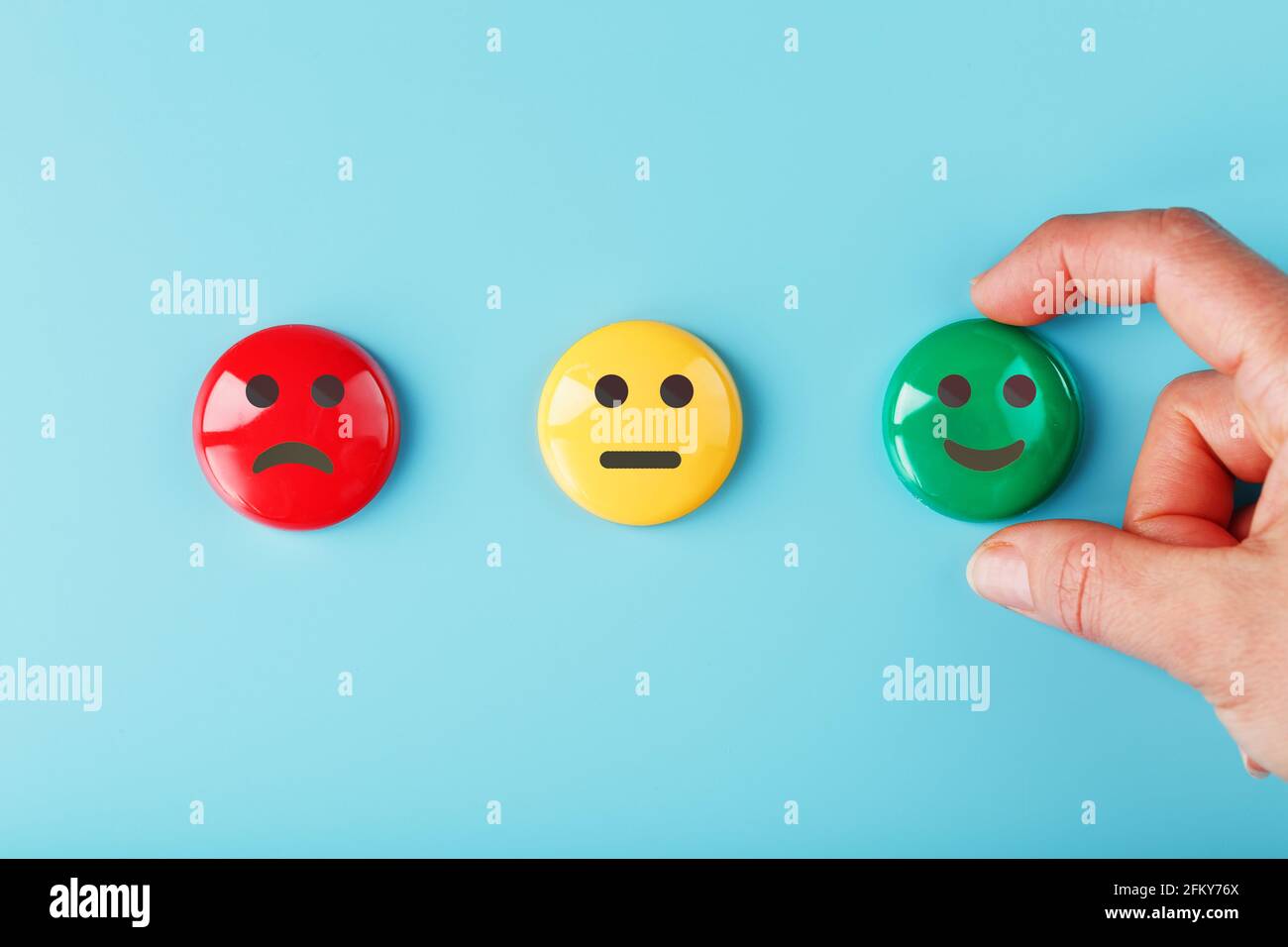 Satisfaction Emotion icons Rouge mécontent, jaune neutre et vert émoticône souriant sur fond bleu avec une main. Feedback, sondage et notation Banque D'Images