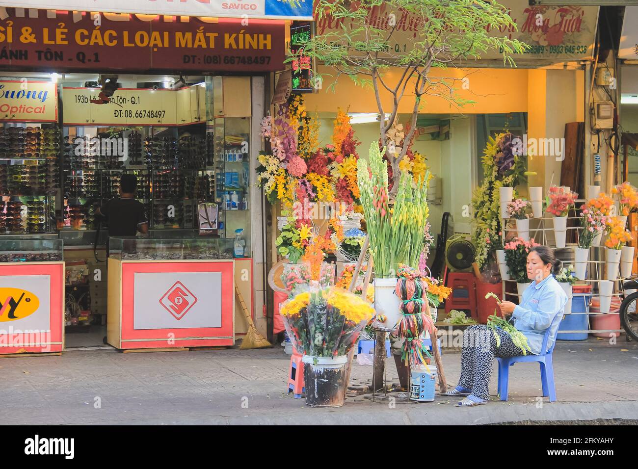 Hanoï, Vietnam - Mars 10 2019: Un fleuriste de rue vietnamien local tond des tiges de fleurs dans les rues de la ville de Ho Chi Minh ville (Saigon). Banque D'Images