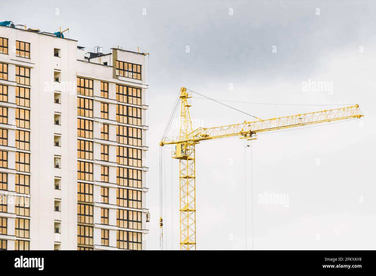 Une grue à tour industrielle construit un nouveau bâtiment moderne de la ville sur un chantier de construction. Développement de bâtiments et travaux d'architecture urbaine. Banque D'Images