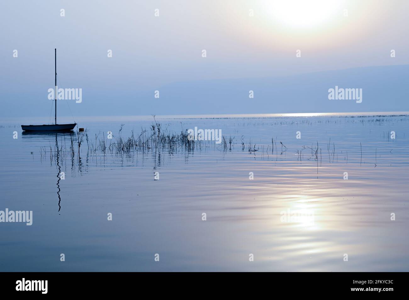 Lever du soleil sur le lac. Bateau flottant sur l'eau calme sous un coucher de soleil étonnant. Banque D'Images