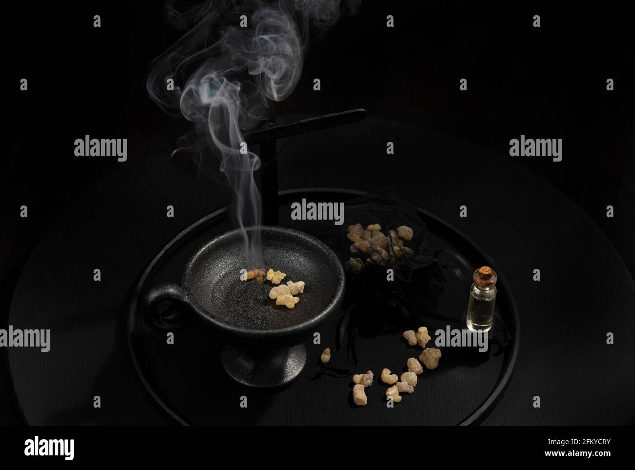 Encens fumeurs, croix, eau sainte, sur fond noir. Image conceptuelle Banque D'Images