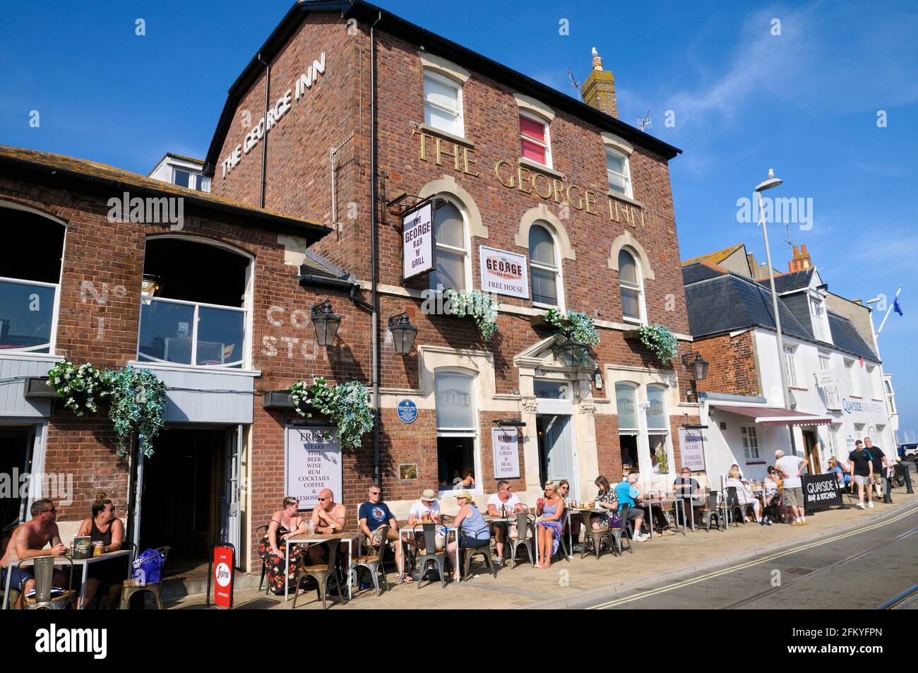 Les personnes qui s'assoyent dehors en prenant un verre sous le soleil d'été au George Bar & Grill, un pub sur le quai de Weymouth, Dorset, Angleterre, Royaume-Uni Banque D'Images