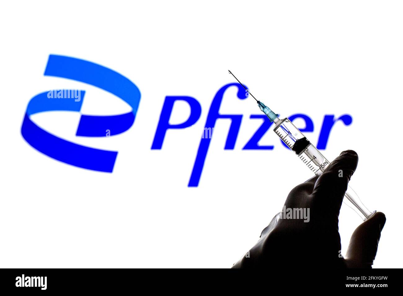 Espagne. 04e mai 2021. Dans cette photo illustration, un gros plan d'une main tenant une seringue médicale devant le nouveau logo Pfizer crédit: SOPA Images Limited/Alay Live News Banque D'Images