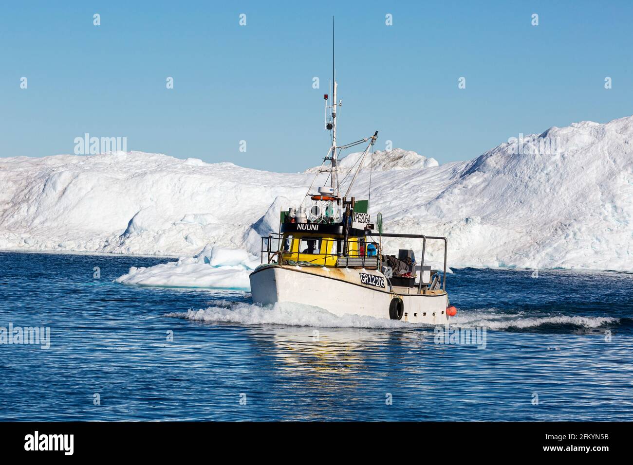 Pêcheur parmi les icebergs vêlé du glacier Jakobshavn Isbræ, site classé au patrimoine mondial de l'UNESCO, Ilulissat, Groenland. Banque D'Images