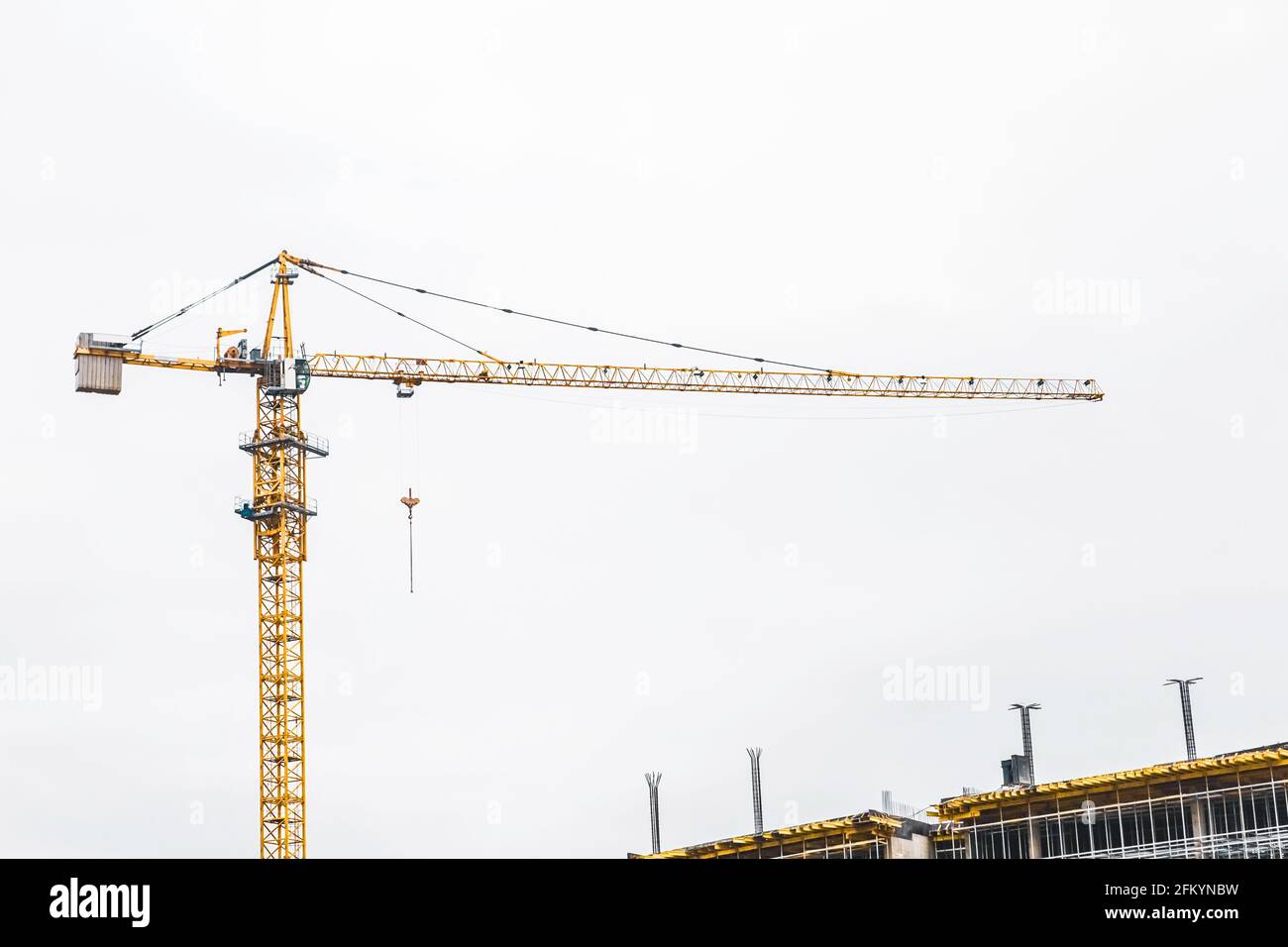 Une grue industrielle à tour construit un nouveau bâtiment de ville en béton ou des appartements sur le chantier de construction. Banque D'Images