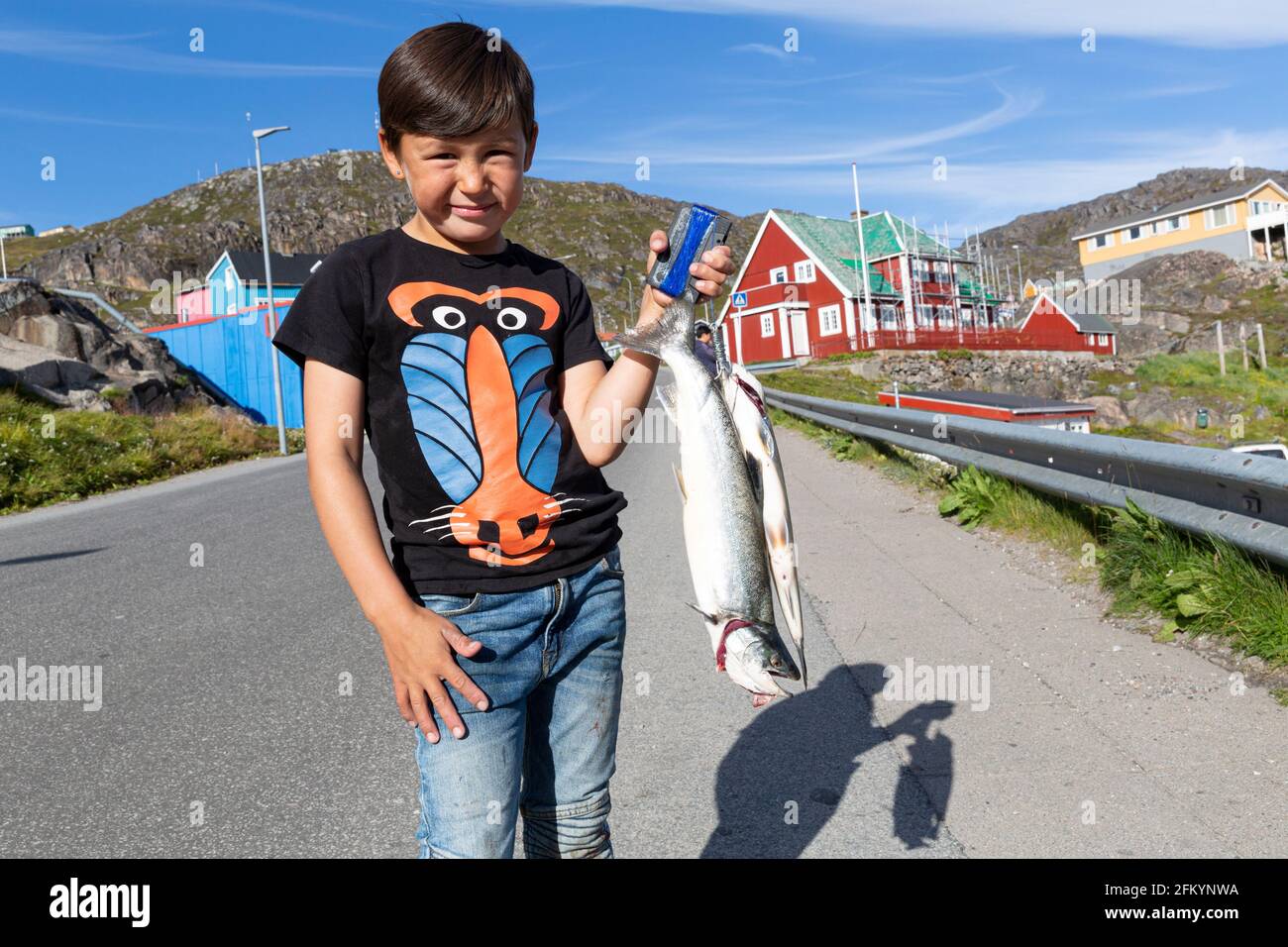Enfant présentant un poisson dans le petit village groenlandais de Qaquortoq, anciennement Julianehåb, Groenland. Banque D'Images