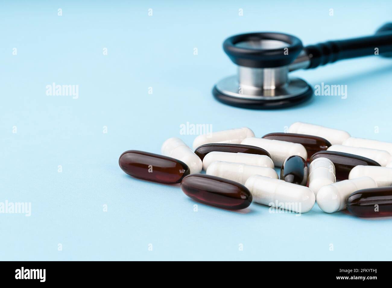 Capsules brunes et blanches assorties, stéthoscope, pilules, isolées sur fond bleu. Compléments nutritionnels pour la perte de poids et l'énergie, aides alimentaires Banque D'Images