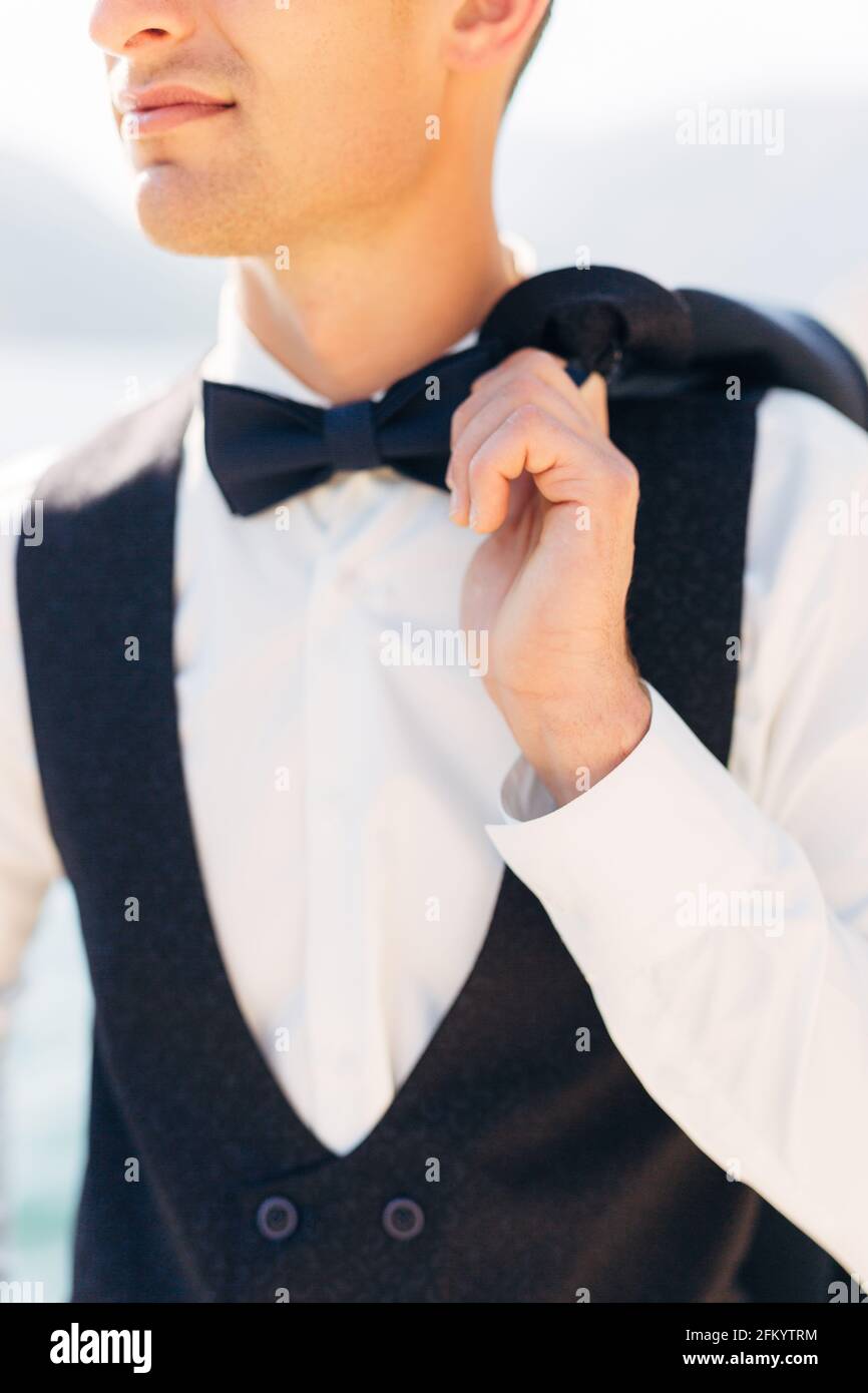 Un homme dans une chemise blanche, un gilet et un noeud papillon tient une  veste jetée par-dessus son épaule Photo Stock - Alamy