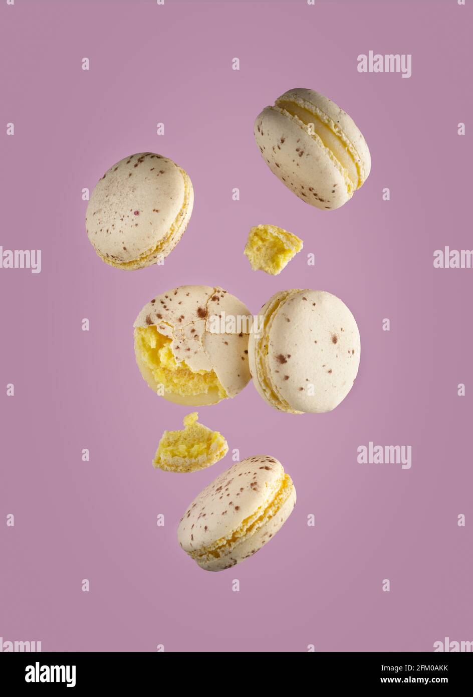 Différents types de macarons en mouvement tombant sur fond rose Banque D'Images