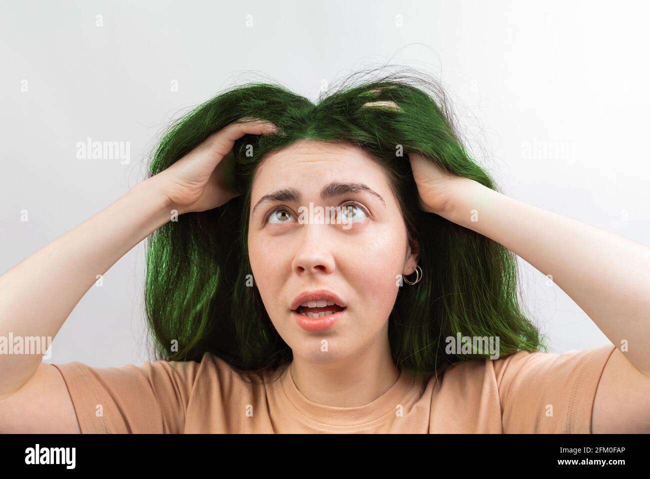 Coloration des cheveux. Une jeune femme de race blanche dans un t-shirt  beige, regardant ses longs cheveux verts dans la friche. Arrière-plan blanc  Photo Stock - Alamy
