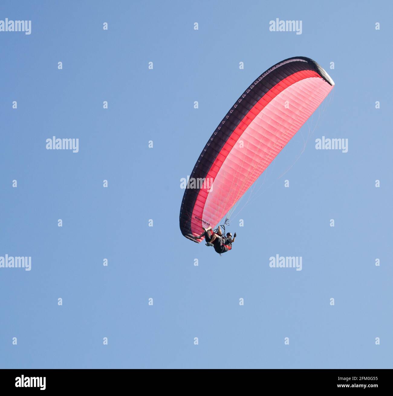 Photos aériennes - vol en parapente en tandem avec du rouge contre le ciel bleu Banque D'Images