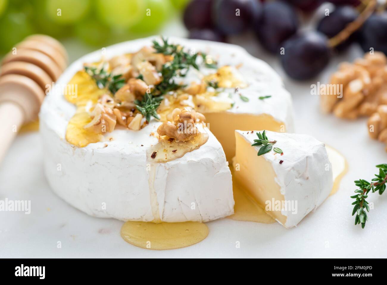 Camembert avec noix et miel sur cheesboard blanc, vue rapprochée. Fromage blanc gastronomique Banque D'Images