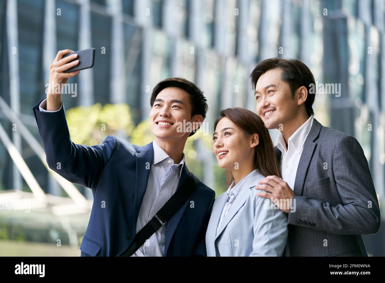 équipe de trois hommes d'affaires asiatiques qui prennent un selfie dans le centre-ville quartier financier de la ville moderne Banque D'Images