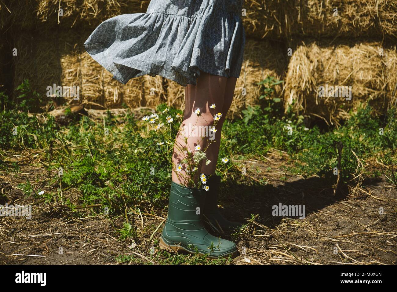 Jeune fille en bottes de caoutchouc avec des fleurs debout contre le fond  de balles de paille sur la ferme de campagne. Agriculture, Cottagecore,  Farmcore, Countrycore Photo Stock - Alamy