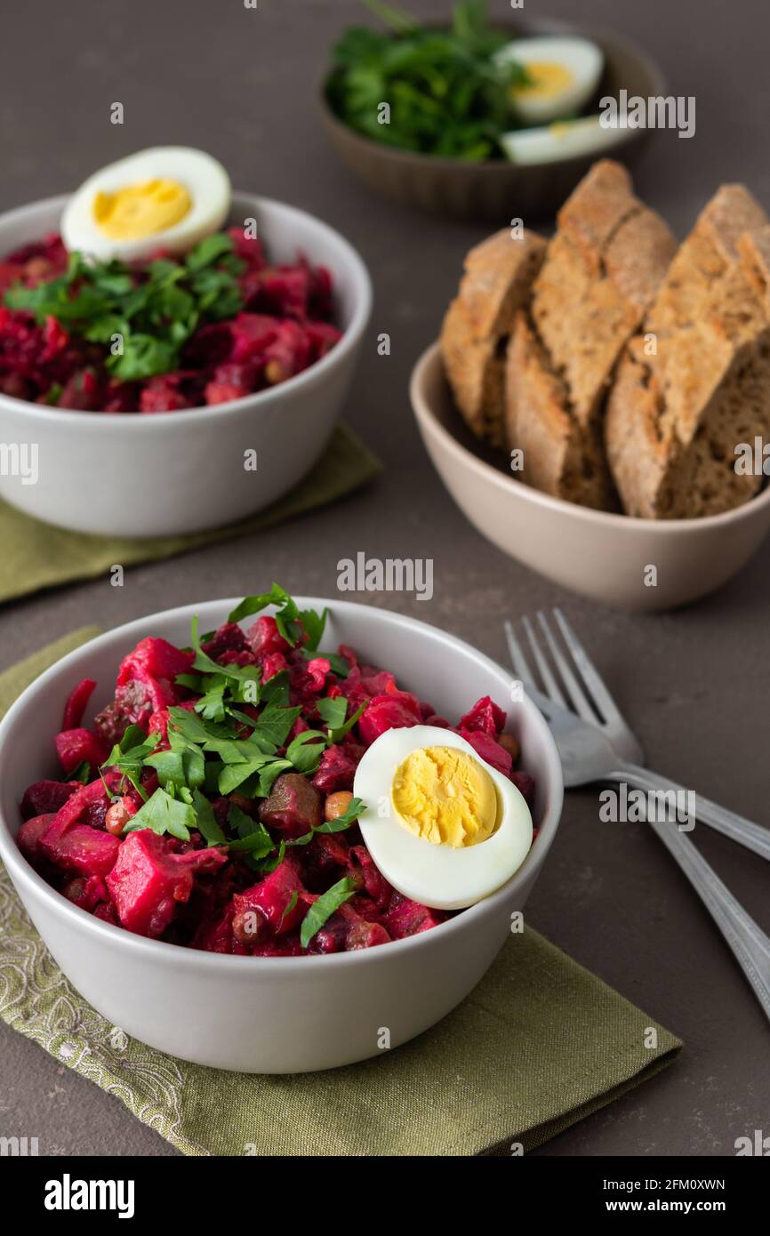 Salade russe vinaigrette dans des assiettes avec oeuf bouilli, salade de pommes de terre bouillies et carottes, betteraves et légumes marinés, concombre et chou Banque D'Images