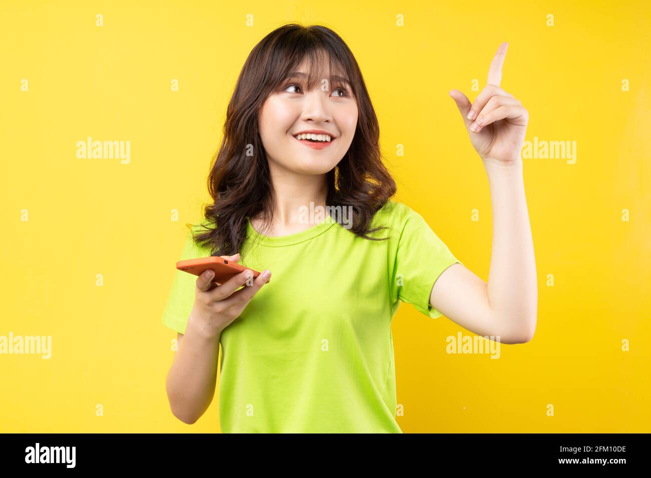 Jeune fille utilisant le téléphone avec l'expression gaie sur fond Banque D'Images