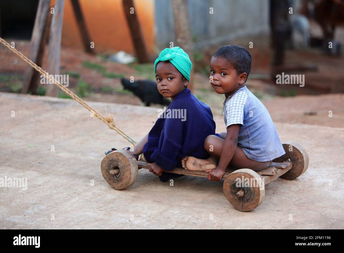 Bhakta tribal petits enfants assis sur une charrette à jouets en bois à Hattaguda Village, Andhra Pradesh, Inde Banque D'Images