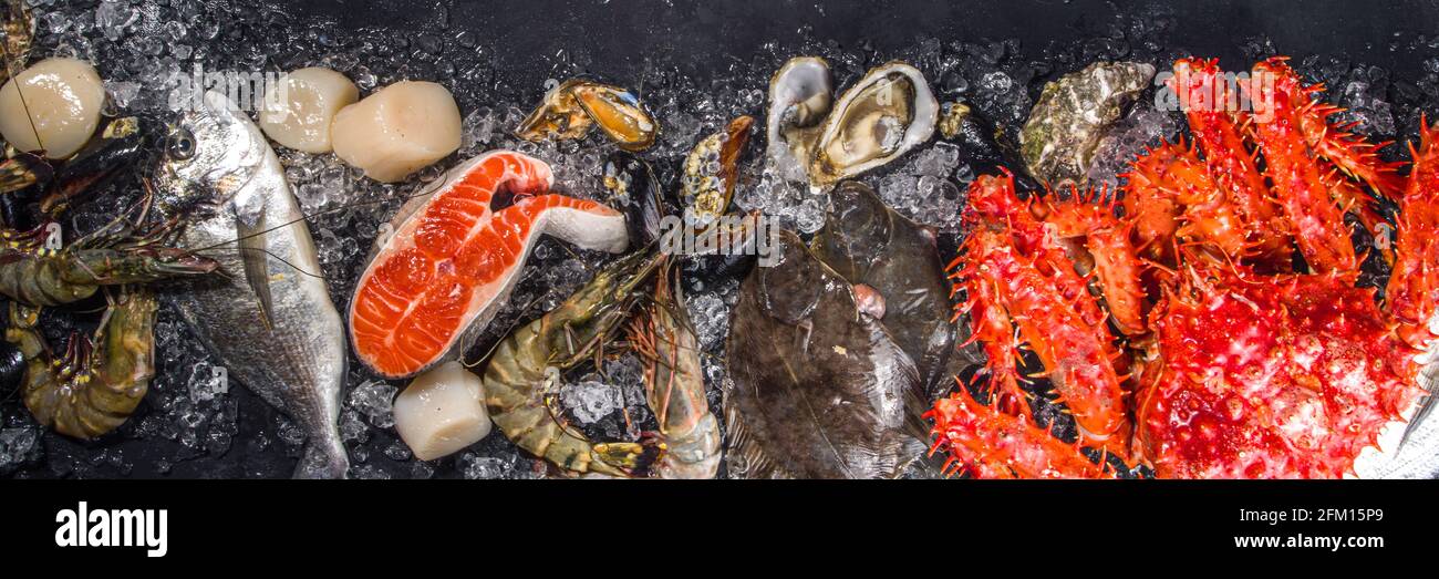 Ensemble de divers fruits de mer frais crus - pieuvre, crabe, calmar, crevettes, huître, moules, saumon thon dorada poisson avec épices d'herbes citron, dos noir Banque D'Images