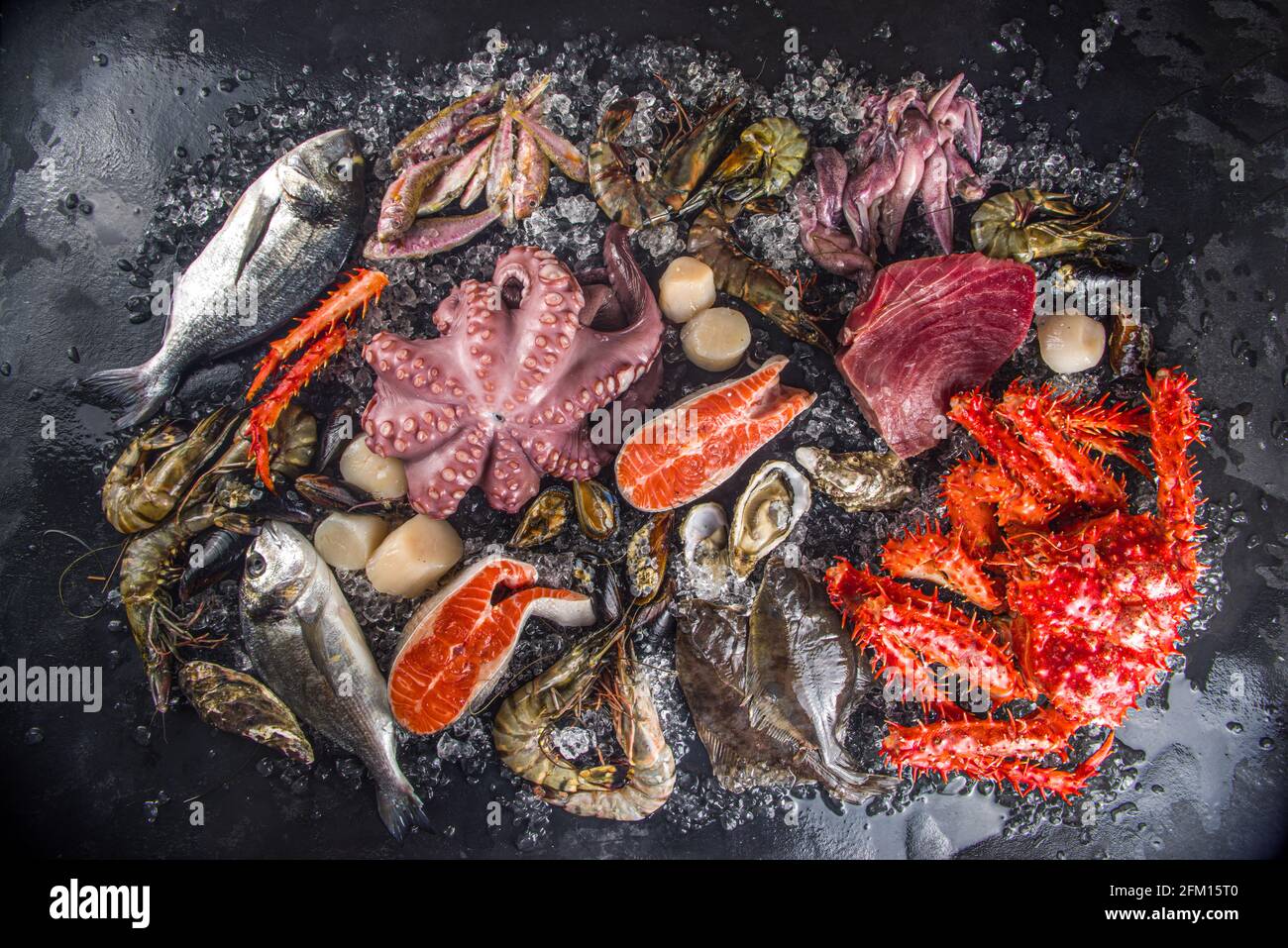 Ensemble de divers fruits de mer frais crus - pieuvre, crabe, calmar, crevettes, huître, moules, saumon thon dorada poisson avec épices d'herbes citron, dos noir Banque D'Images