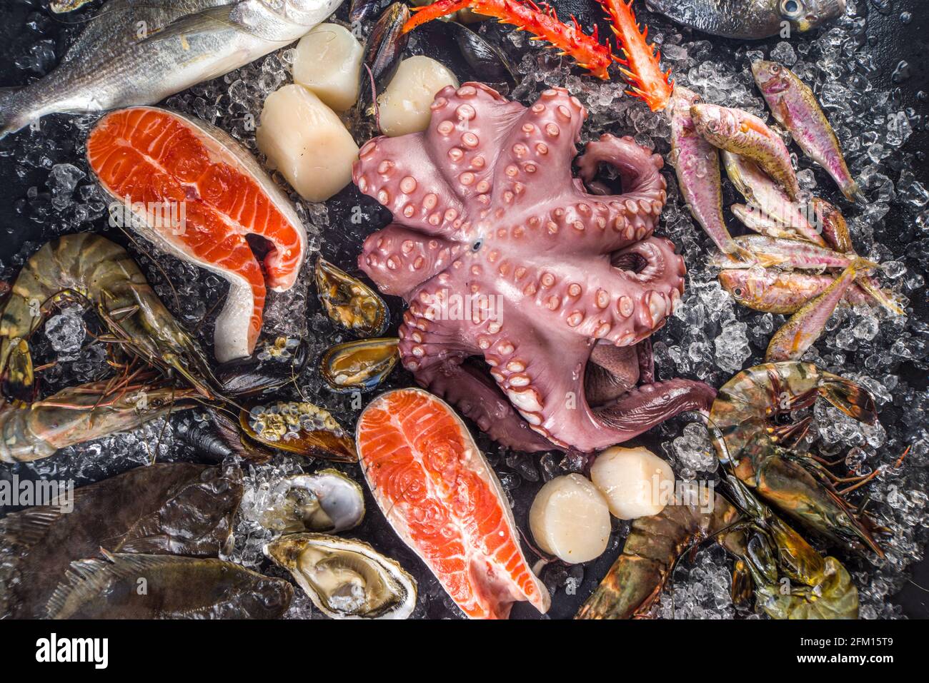 Ensemble de divers fruits de mer frais crus - pieuvre, crabe, calmar, crevettes, huître, moules, saumon thon dorada poisson avec épices d'herbes citron, dos noir Banque D'Images