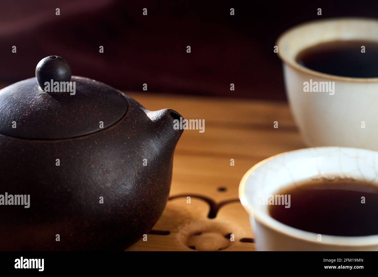 Cérémonie du thé gong fu cha. Théière chinoise à l'argile de zisha au jaune violet fait à la main avec shu pu erh et deux bols en porcelaine de celadon tasse à thé sur bambou Banque D'Images