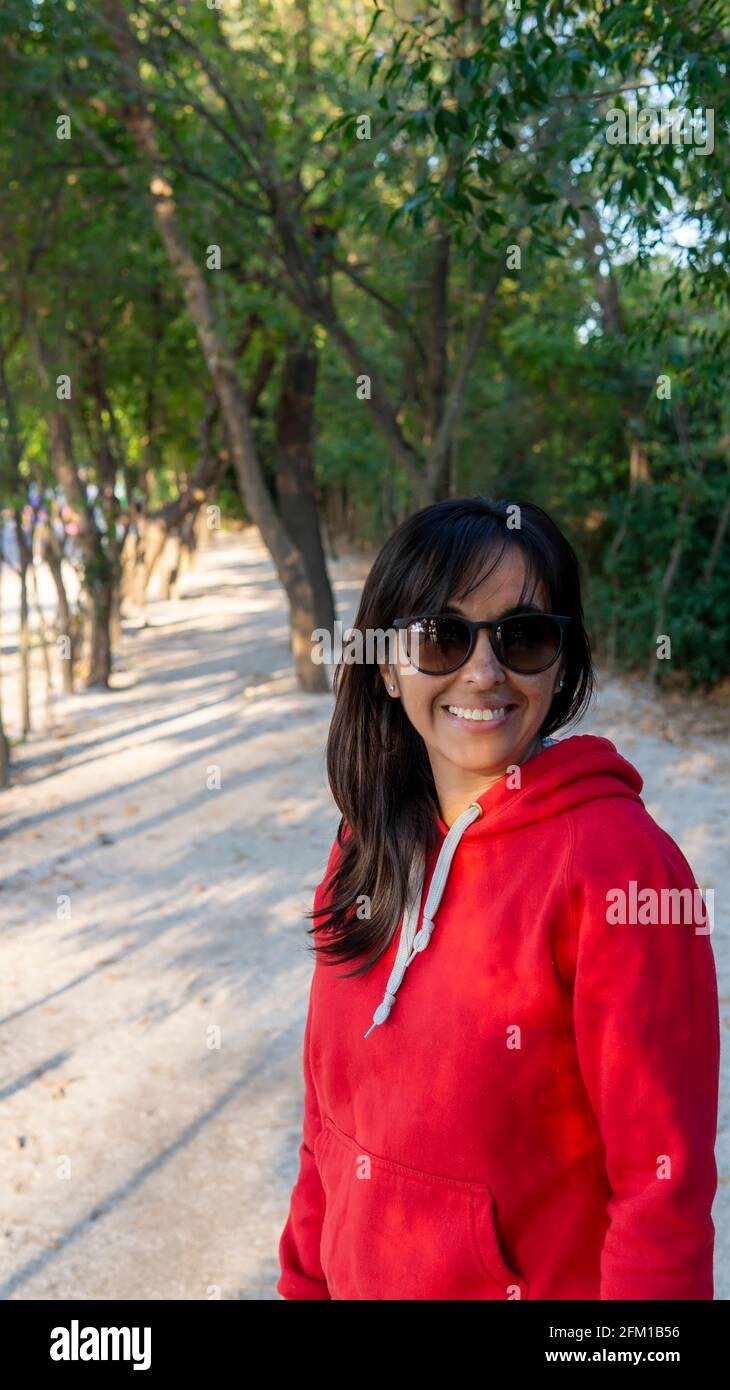 portrait d'une jeune femme portant des lunettes de soleil dans un vert garez-vous au coucher du soleil Banque D'Images