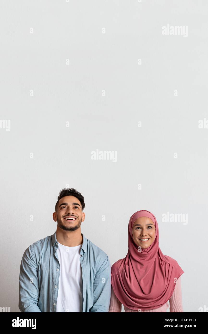 Un homme et une femme arabes heureux dans le hijab regardant vers le haut copier l'espace Banque D'Images