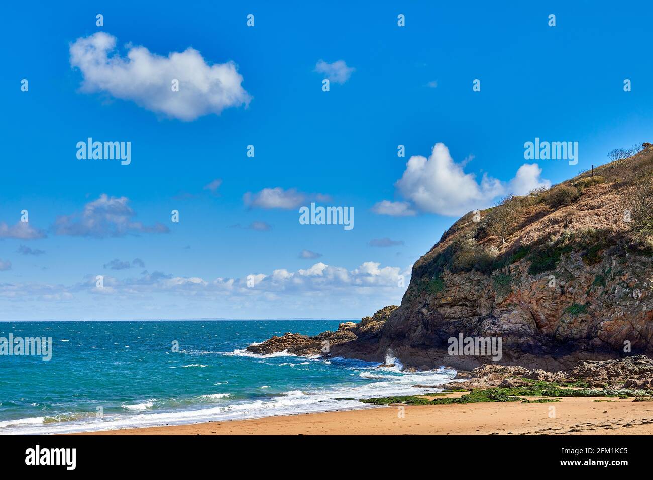 Image de la section est de Geve le Lecq, ci de Jersey avec sable, rochers, promontoire et mer bâclée au soleil avec un peu de nuages Banque D'Images