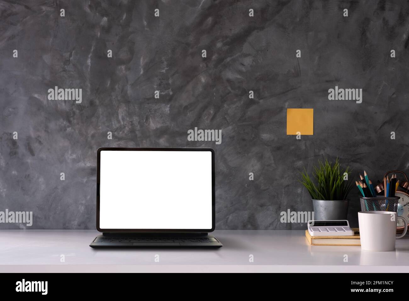 Espace de travail avec blanc blanc sur tablette pc, livres et pot d'arbre sur table en bois avec salon mur en béton loft Banque D'Images