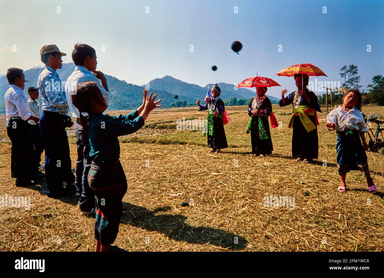 Les femmes Hmong, vêtues de costumes traditionnels et portant des parasols, saluent le nouvel an en jouant au ballon. Le jeu de balle avec les hommes offre l'opportunité Banque D'Images