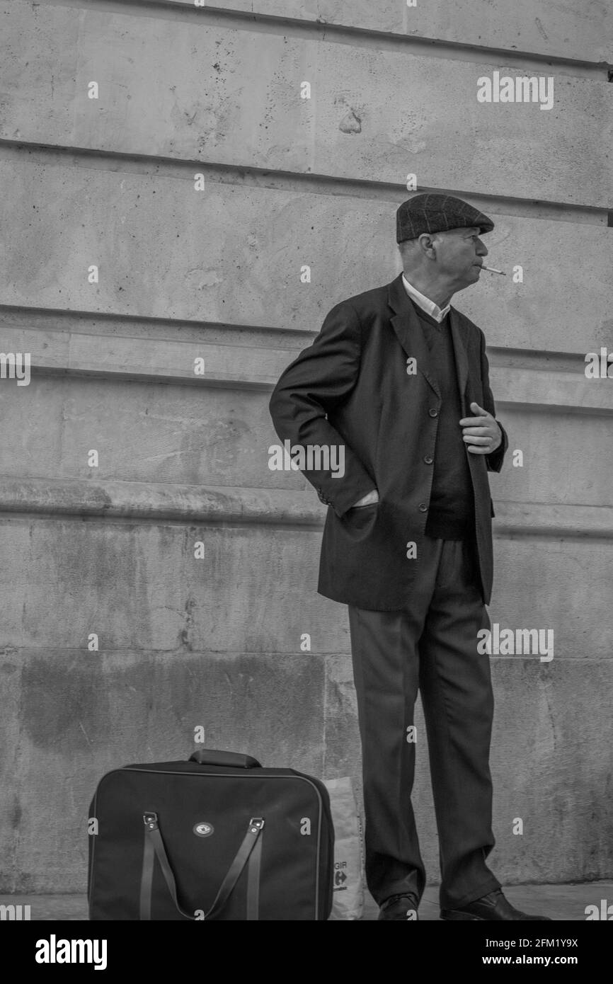 Photographie en noir et blanc d'un voyageur portant une casquette debout et attendant près d'un mur de maison en Espagne Banque D'Images