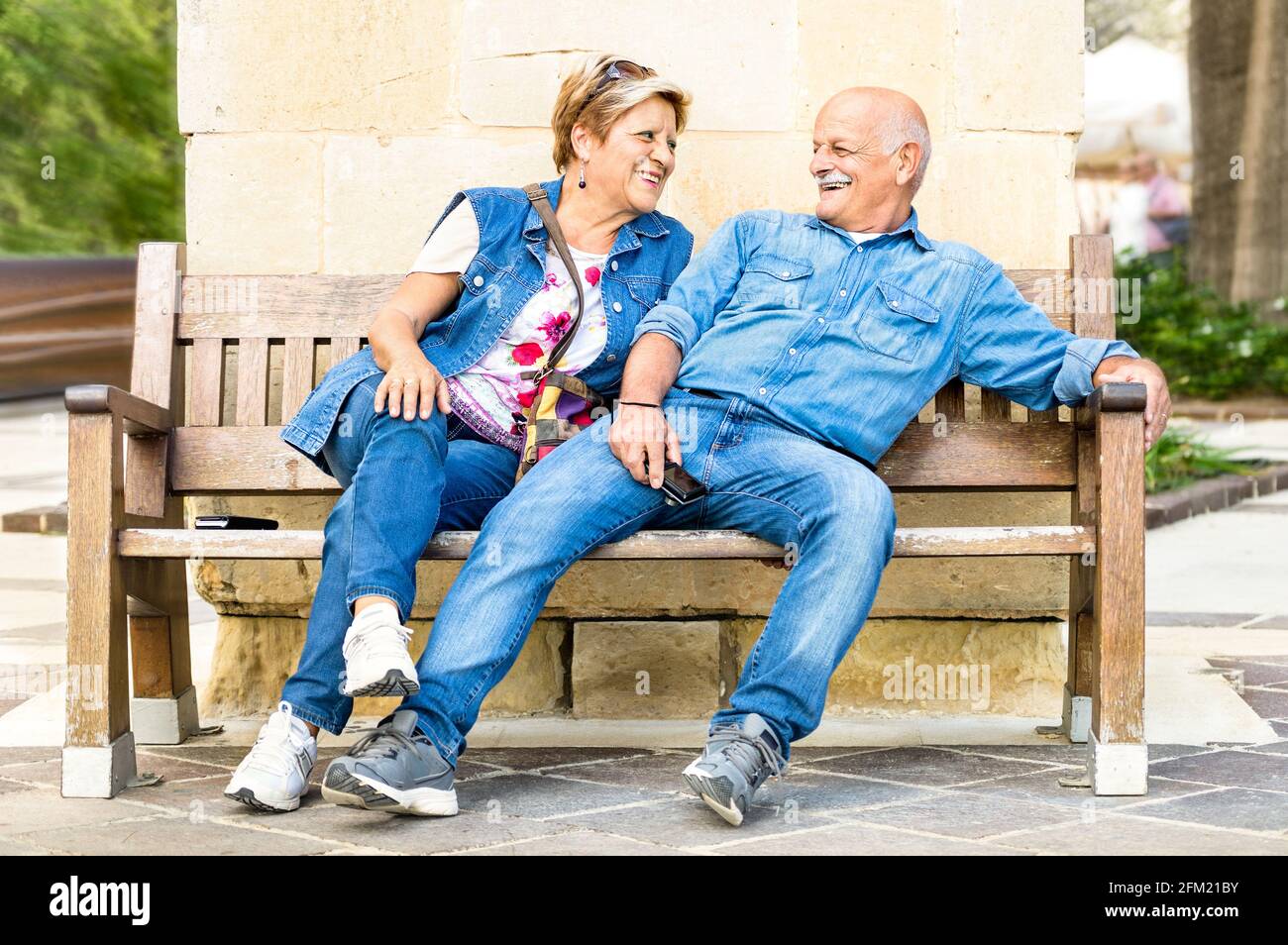 Couple senior heureux s'amuser sur un banc - concept De personnes âgées actives et joueuses à la retraite - mode de vie quotidien après-midi ensoleillé en automne Banque D'Images