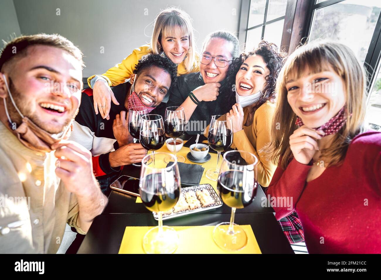 Amis prenant selfie à la cave avec masque ouvert - Les gens qui s'amusent ensemble à boire des verres à vin rouge au restaurant réouverture Banque D'Images