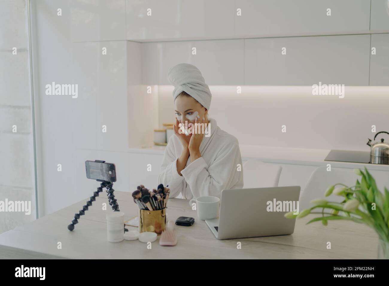 Femme blogueuse de beauté en peignoir et serviette sur l'enregistrement de la tête vidéo sur smartphone pour son vlog Banque D'Images