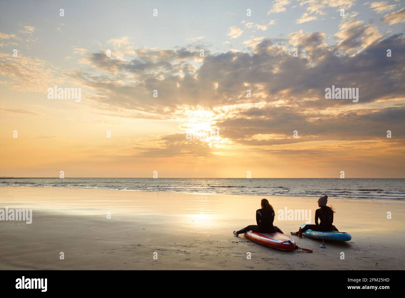 Paddleboarders assis sur leurs planches à regarder le lever du soleil, Sunny Sands, Folkestone, Kent, Angleterre Banque D'Images