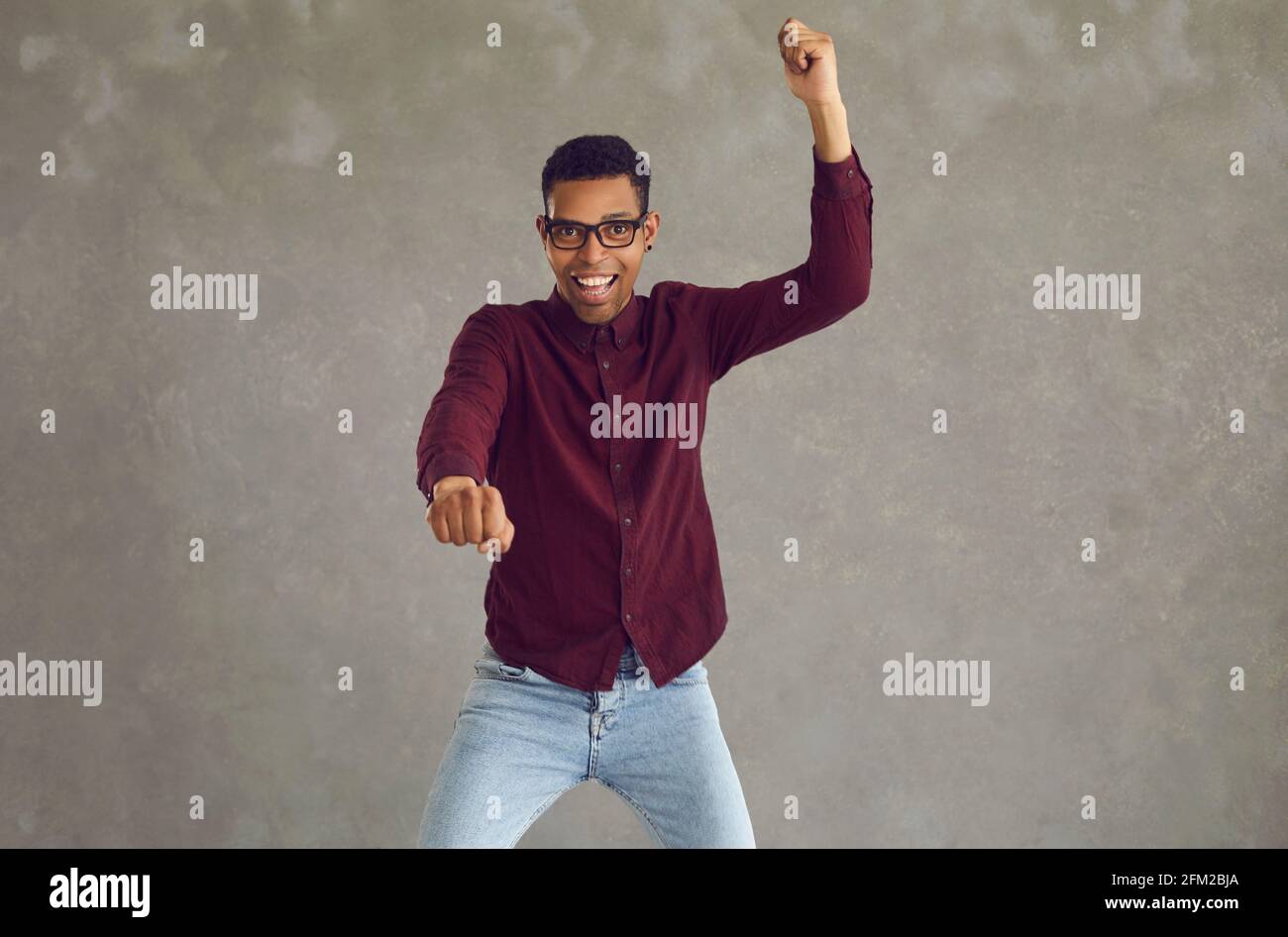 Un jeune homme afro-américain se réjouit de son succès avec un studio de poings serrés prise de vue Banque D'Images