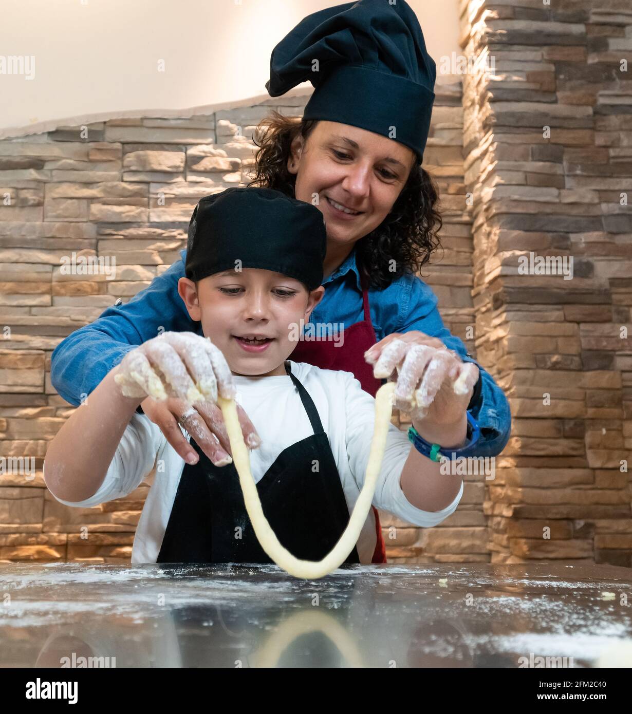 Mère et fils cuisant une pâtisserie ensemble dans les costumes du chef Banque D'Images