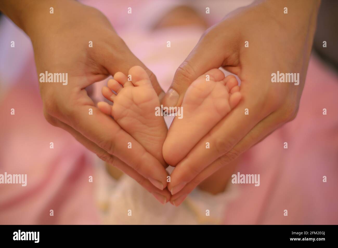Les pieds de bébé nouveau-né dans les mains de sa mère en forme de coeur. Mère montrant son amour et son affection. Banque D'Images