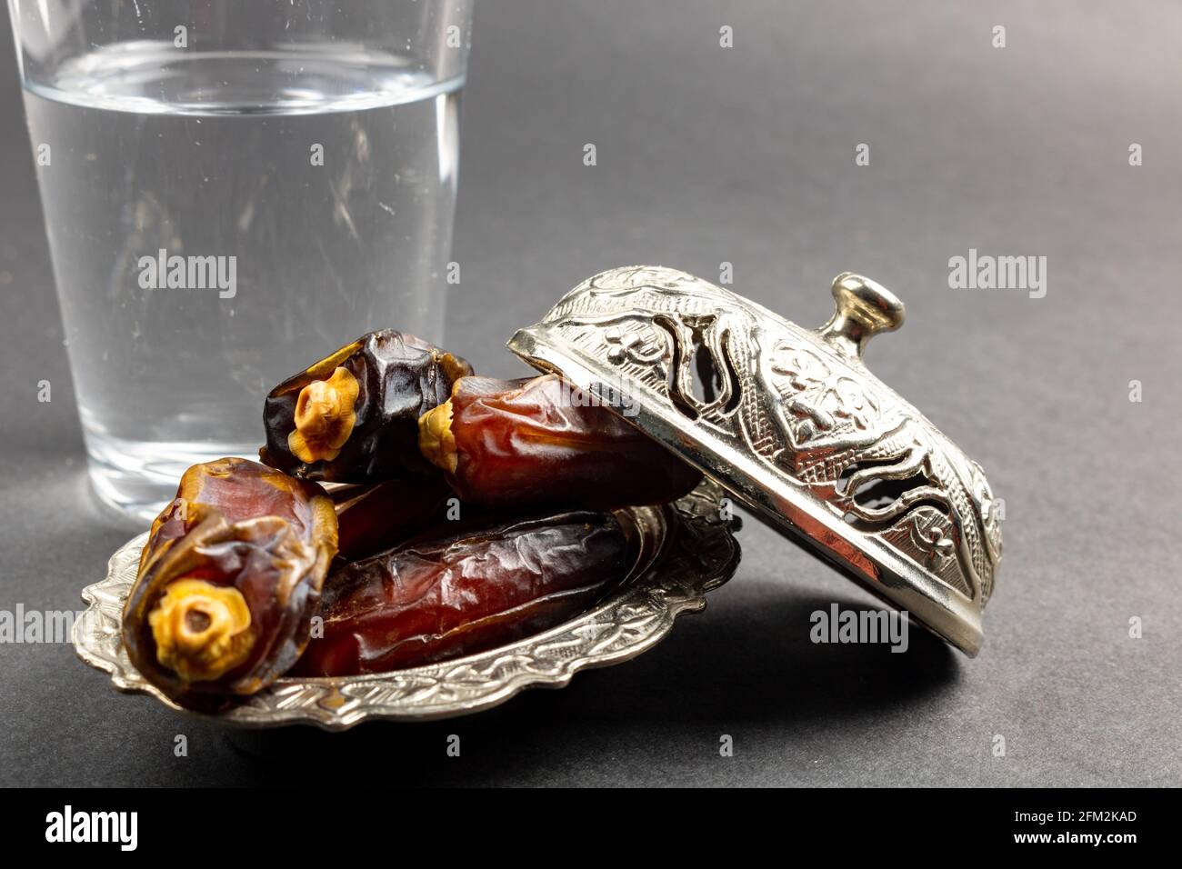 dates sur le bol et un verre d'eau sur fond gris. Photo de haute qualité. Aliments et en-cas du ramadan. Fête de l'iftar. Jeûne en ramadan. Banque D'Images