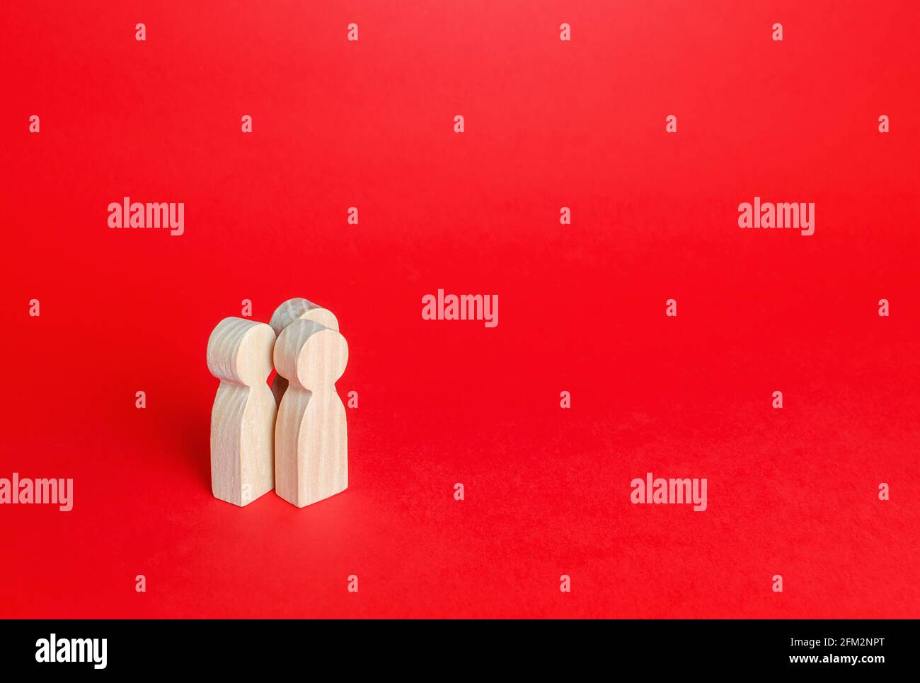 Trois figurines humaines sur fond rouge. Communication et discussion. Relations amicales. Une réunion. Assistance, coopération et collaboration. PLA Banque D'Images