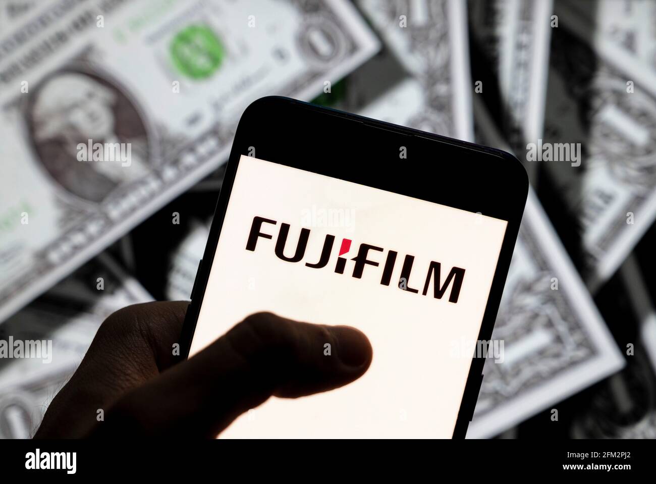 Sur cette photo, le logo de la société japonaise de photographie et d'imagerie Fujifilm est affiché sur un smartphone avec une devise en dollars américains (USD) en arrière-plan. Banque D'Images