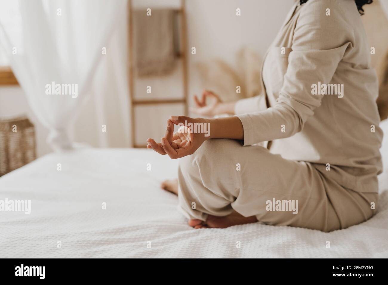 Image rognée d'une femme afro-américaine pratiquant des exercices de yoga et de relaxation au lit. Banque D'Images