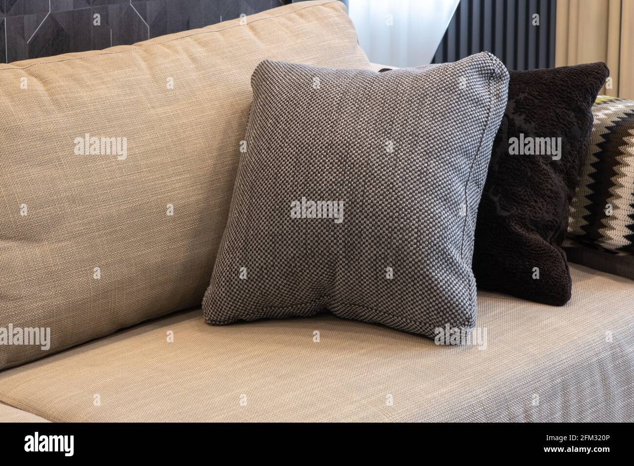 Intérieur confortable. Oreillers décoratifs aux couleurs neutres, tissu écossais sur canapé beige. Concept Home Comfort, textiles, accessoires décoratifs pour un Banque D'Images